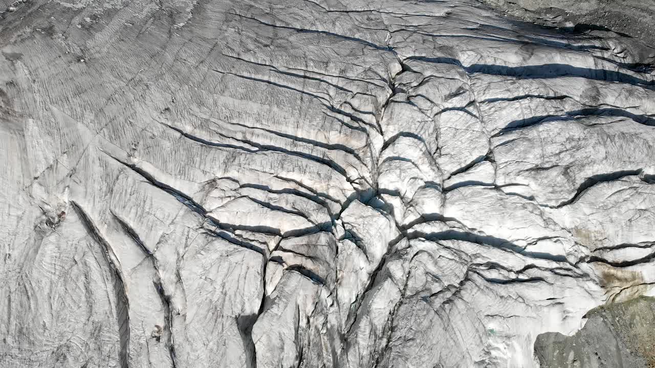 Aerial flyover over a glacier near Arolla in Valais, Switzerland with a spinning panning view from the glacier ice towards the sunlit Val d'Herens valley