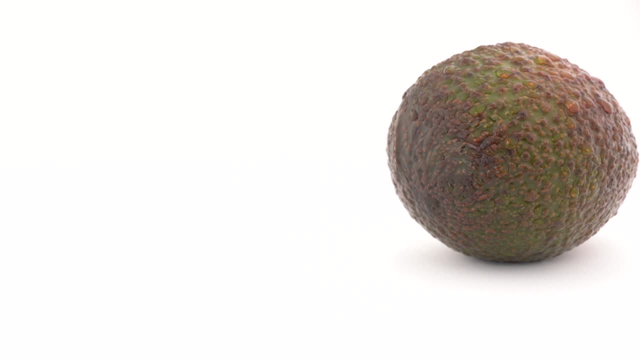 la cámara está llegando a un aguacate girando lentamente, aislado sobre un fondo blanco. macro en primer plano.