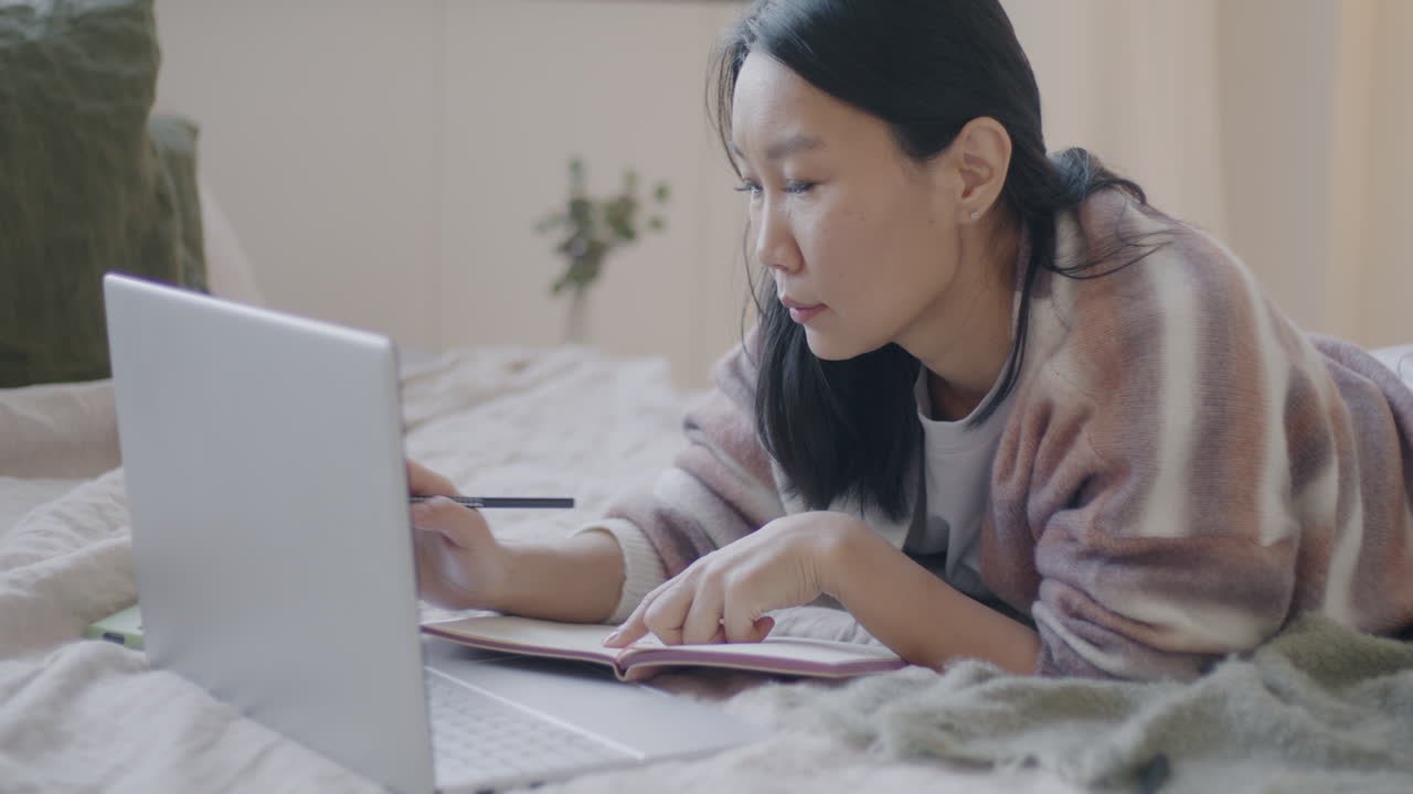 Woman working from bed on laptop