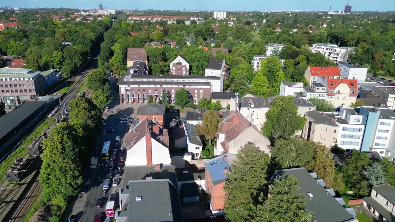 Berlin Zehlendorf: Stadtteil mit Gebäuden und S-Bahn-Station an einem sonnigen Sommertag. Majestätische Drohnenaufnahme aus der Vogelperspektive.