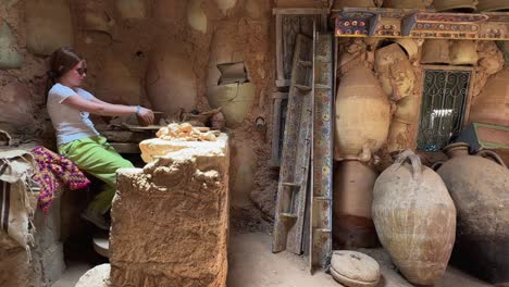 little tourist girl at work with clay in rural pottery workshop of tunisia