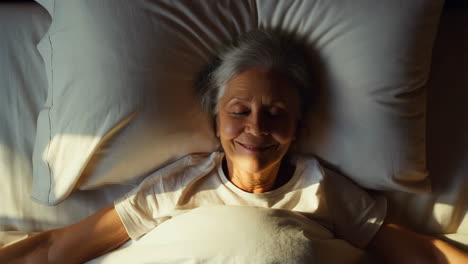 senior woman wakes up and stretches in bed in morning light
