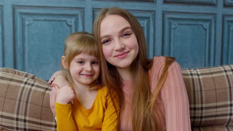 portrait of satisfied child kid daughter with young mother, hugging, embracing, showing thumbs up