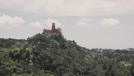 Iconic-Palace-of-Pena-on-top-of-forestry-mountain-in-Portugal,-handheld-view