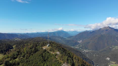 communications antenna on summit of vast mountain peak valley lush green hillside aerial pull back