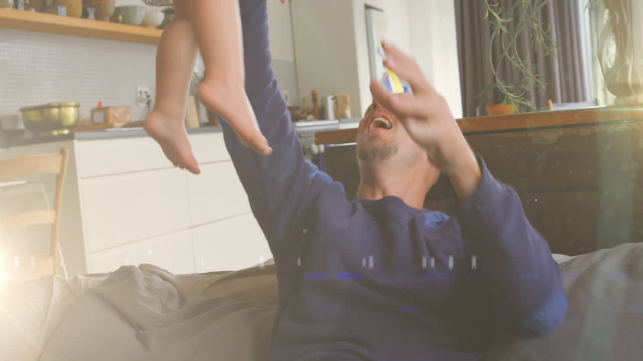 animación de puntos de luz sobre un padre caucásico feliz sosteniendo a su hija en casa