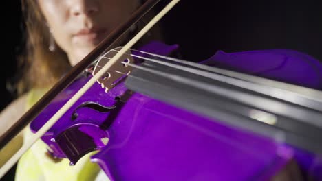 un primer plano de una joven tocando el violín en el escenario.