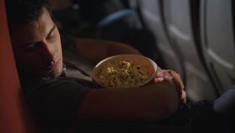 Sleeping-man-embracing-popcorn-box-at-cinema.-Guy-sleeping-in-chair-at-cinema