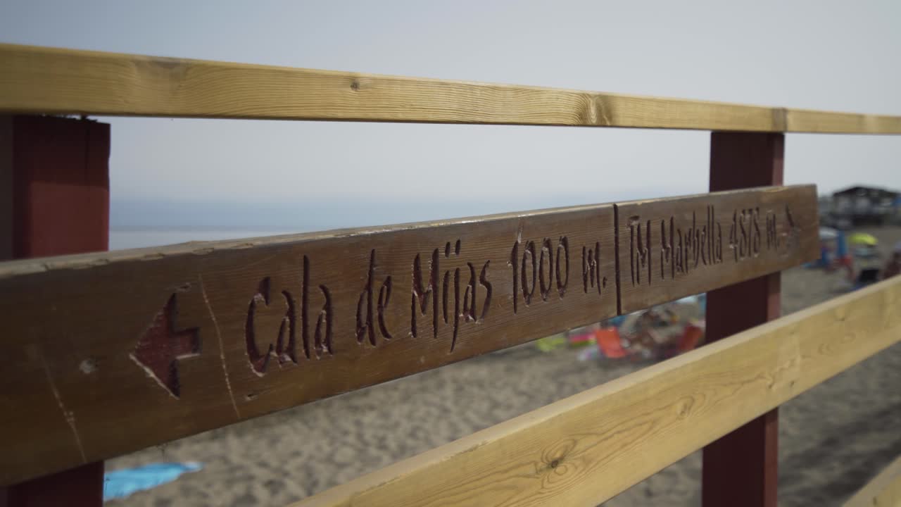 Uma placa de madeira esculpida com os dizeres Cala De Mijas no início do calçadão na praia perto de Cala De Mijas.