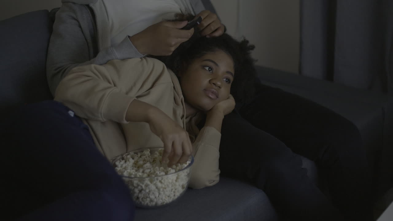 Young Woman Watching A Movie And Eating Popcorn Leaning On Her Boyfriend's Lap