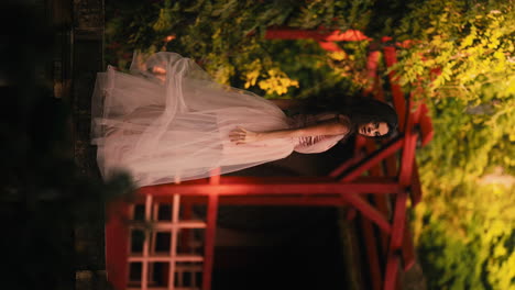 attractive brunette woman waving her long pink dress in a japanese garden at sunset