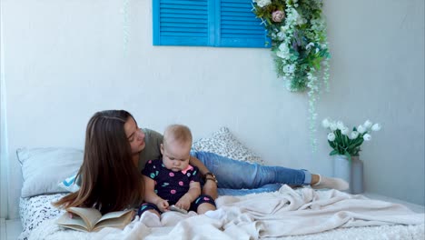 mother and baby reading together on a bed