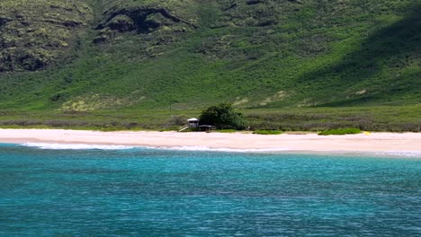 lone lifeguard tower on a remote sand beach at the base of a mountain in oahu
