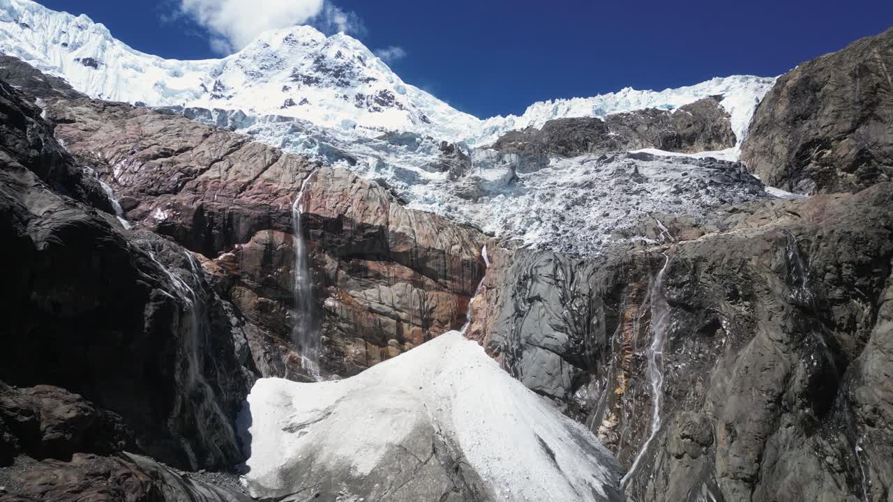 Aerial flight toward waterfalls on rock below Huantsan glacier, Peru
