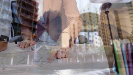 personas en la oficina discutiendo un plan de piso y un fondo de edificios