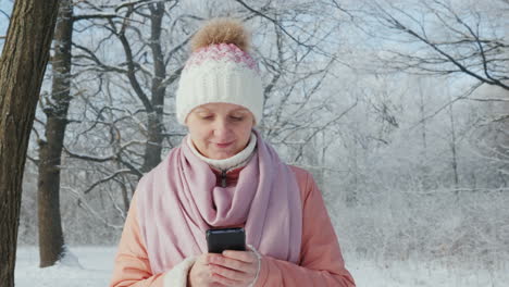 mujer joven camina en el parque de invierno disfruta de video en cámara lenta de smartphone 4k