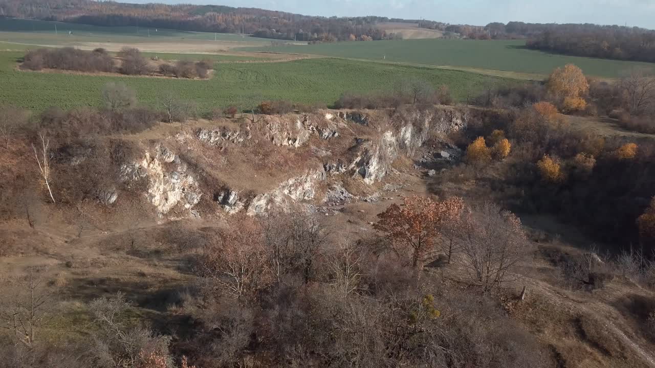 vista aérea de arriba hacia abajo de los árboles de otoño hacia el valle vacío con un enorme campo verde en el fondo