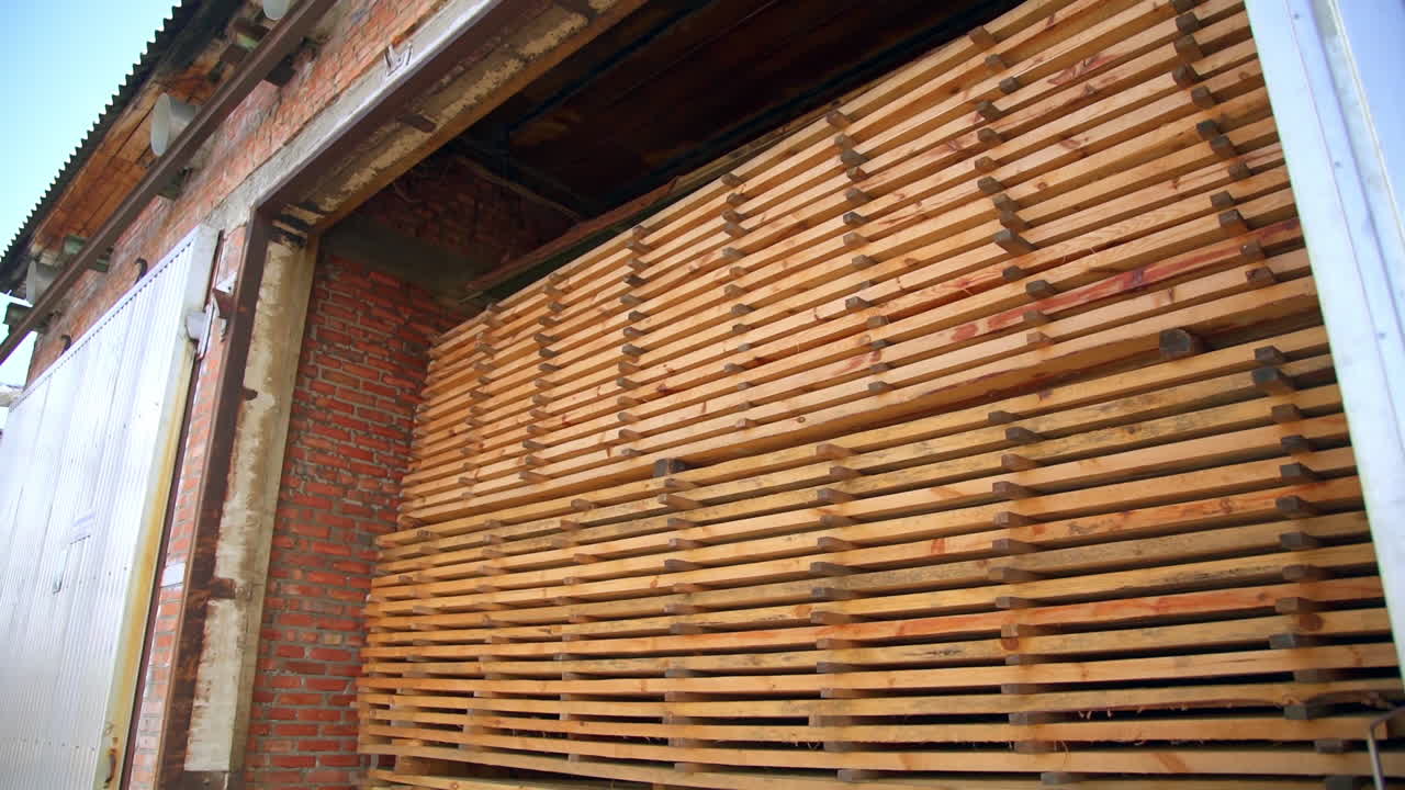 Wooden planks piled in a warehouse up to the top. Timber prepared and stored for modern door production.