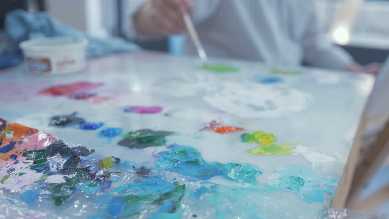 아티스트는 생생한 색상으로 색상 팔레트의 페인트를 브러쉬합니다.