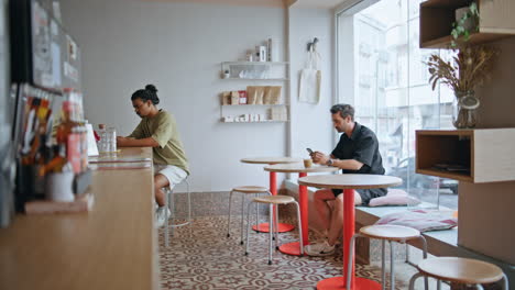 two coffee shop clients sitting separately in cozy interior. men enjoying drink