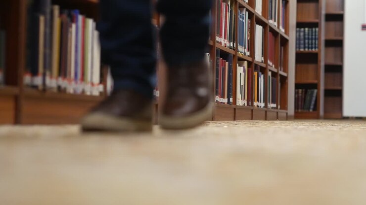 Low angle shot of a person's legs walking towards camera in the library