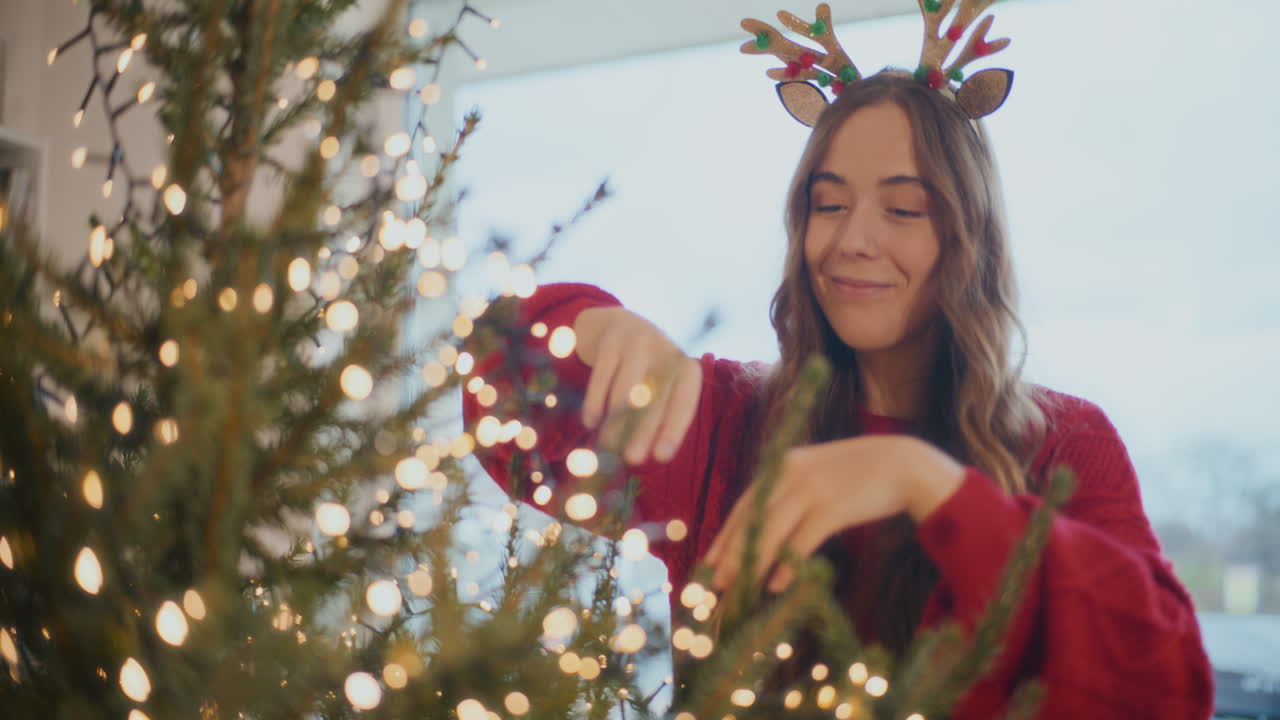 joven ajustando las luces de led en el árbol de navidad