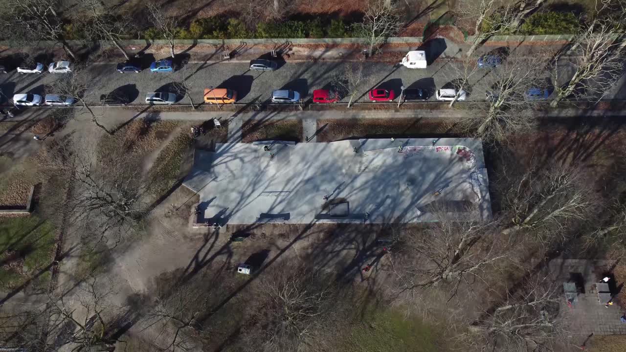 Aerial view of a Berlin skate park during mild winter, showing skaters, urban landscape, and cold-season city vibes