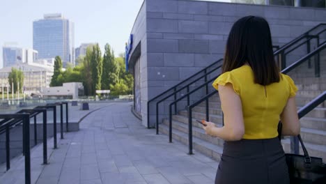 mujer de negocios usando el teléfono mientras camina a la oficina