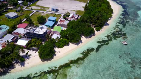 houses and hotels on a very populated area of tropical island in bali, with white beach washed by lagoon full of green algae thriving into warm water