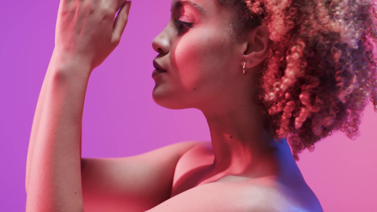 mujer biracial con cabello oscuro en luz azul y rosa, cámara lenta