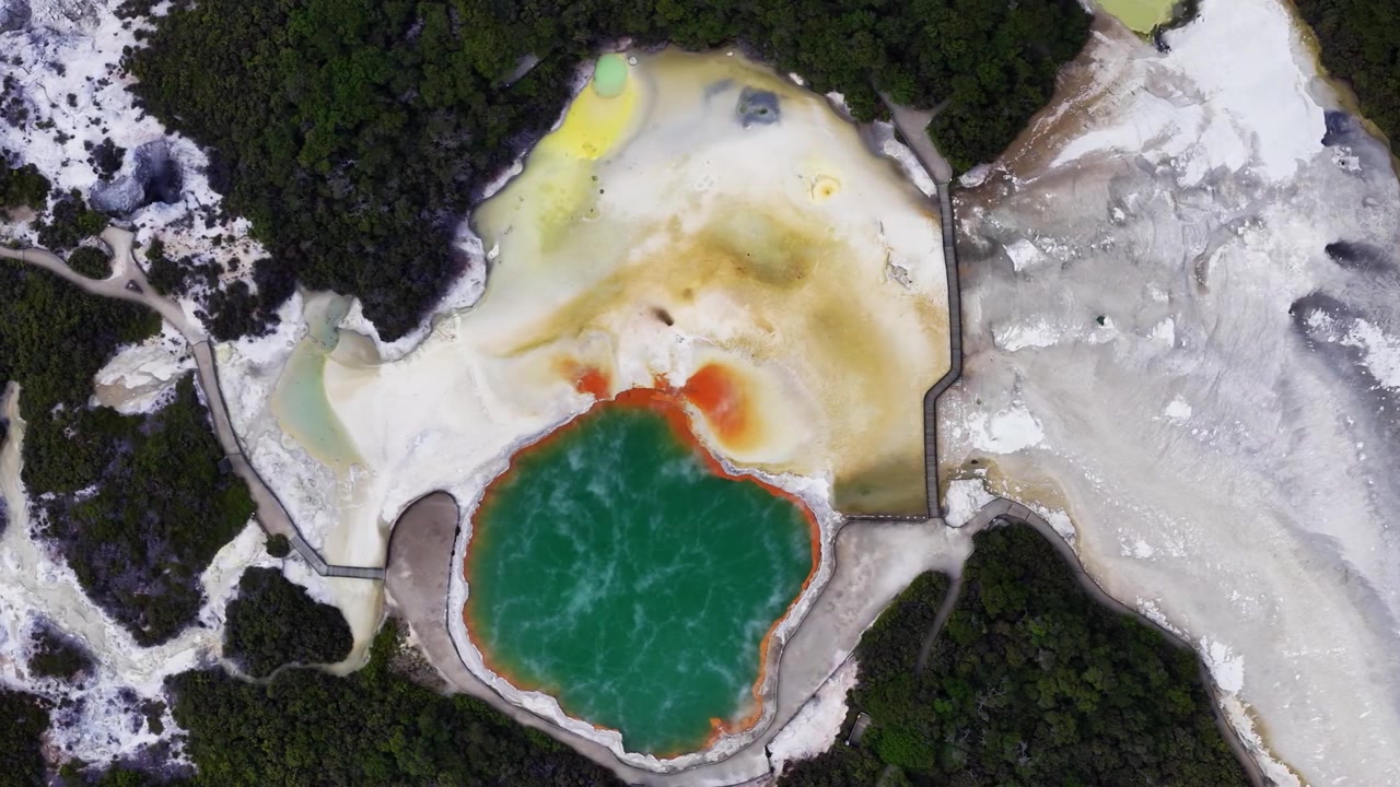 Geotermální horký pramen Rotorua Champagne Pool v zátoce Bay of Plenty, Severní ostrov, Nový Zéland, letecký záběr dronem na barevný termální bazén, sopečnou krajinu, napařující se minerální útvary a geotermální park