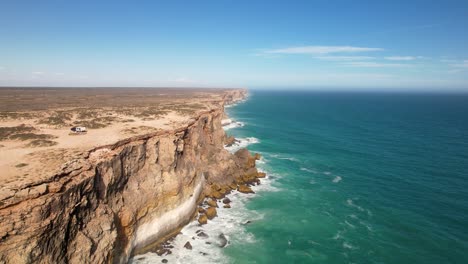 drone view of impressive tall cliffs and the waves crashing against them below