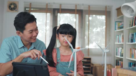 an adult asian father teach his young daughter about clean energy