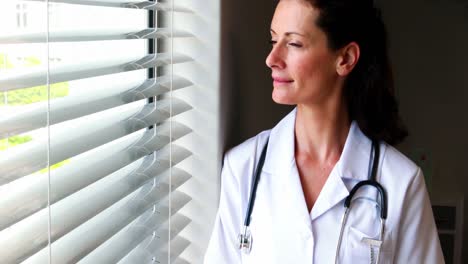 Ärztin-Hält-Klemmbrett-In-Der-Hand-Und-Schaut-Durch-Das-Fenster