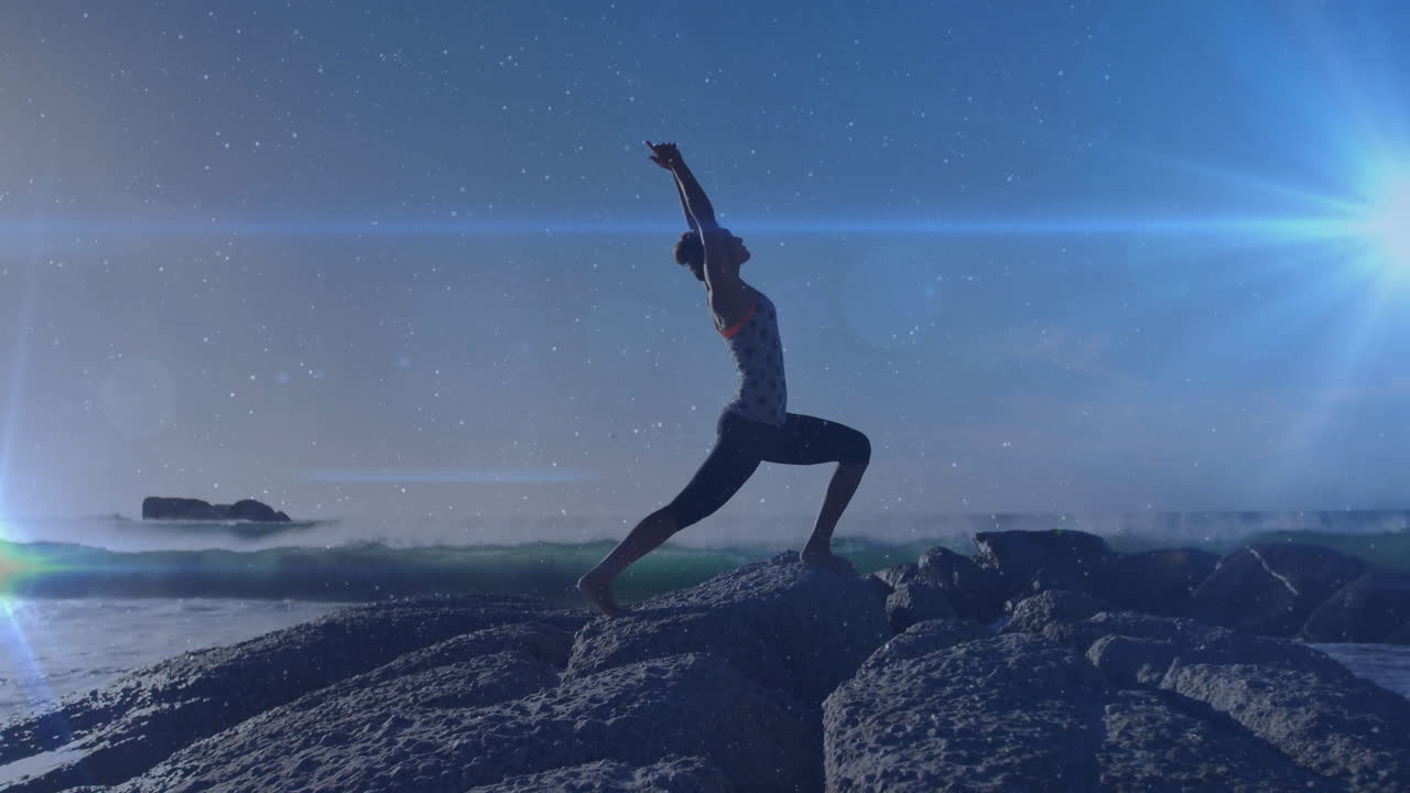 해변에서 요가를 연습하는 두 인종의 여성에 대한 빛의 점의 애니메이션