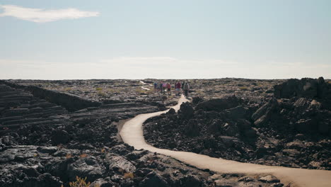 hikers on a winding path through a vast volcanic lava field