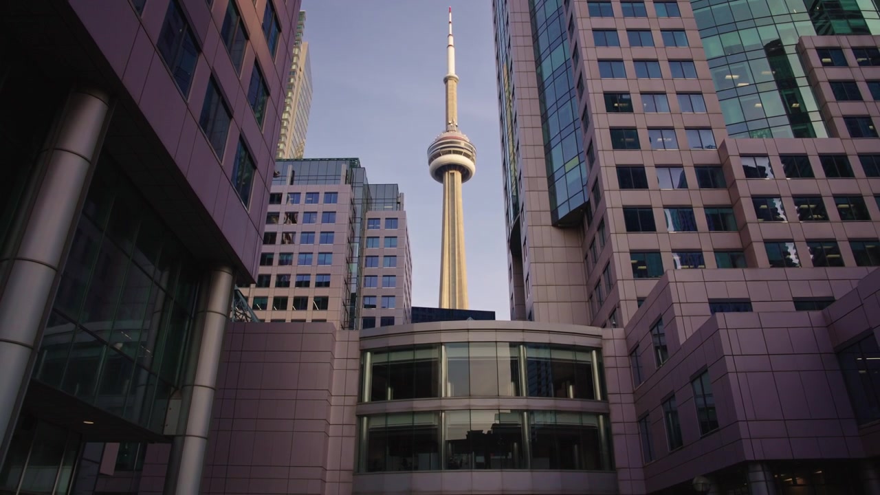 La telecamera si inclina verso il basso mentre si sposta all'indietro per rivelare la CN Tower incorniciata dagli edifici del centro