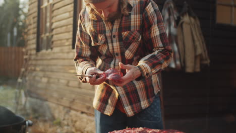 hombre cortando un pedazo de carne para cocinar en barbacoa