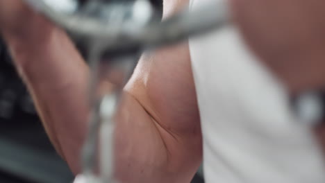 fitness enthusiast grips cable chain handle pulling weight stack with forearm and bicep contracting in focused strength training inside modern gym under bright lighting and blurred equipment backdrop