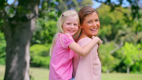 woman lifts her daughter into a piggyback before smiling