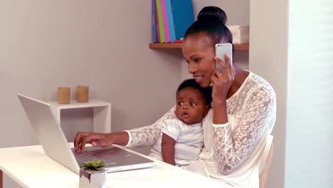 Mujer-Hablando-Por-Teléfono-Sosteniendo-A-Un-Bebé