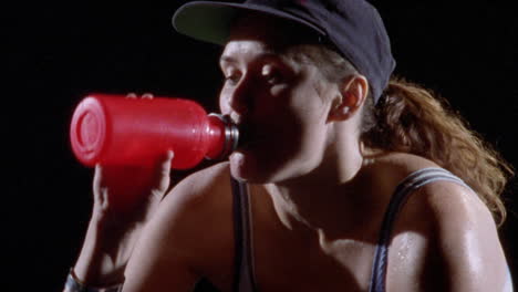 a woman drinks water from a plastic bottle