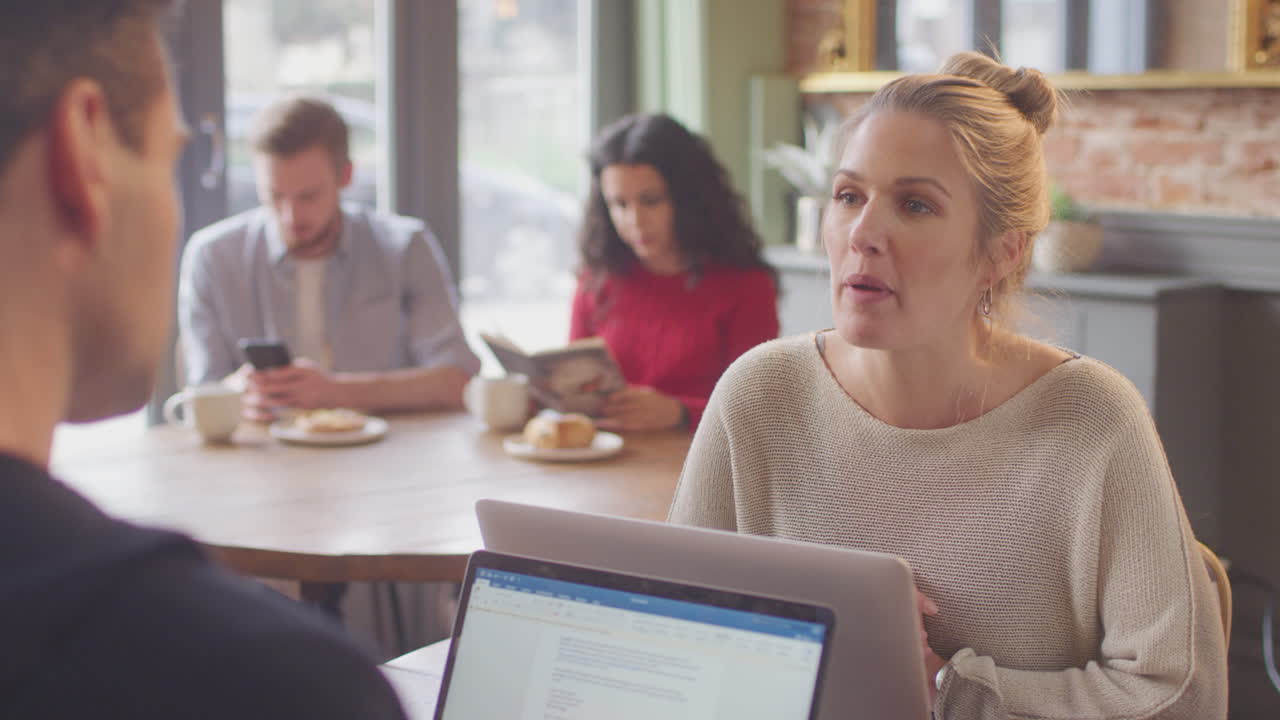 pareja de negocios con computadoras portátiles reuniéndose y trabajando en una cafetería juntos