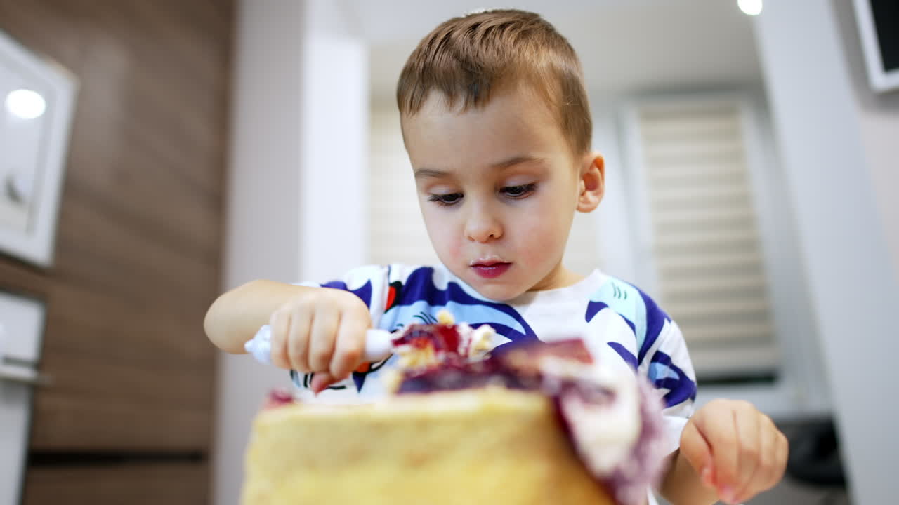 Cute Caucasian baby eating a cake. Low angle view at the toddler boy enjoying sweet dessert.