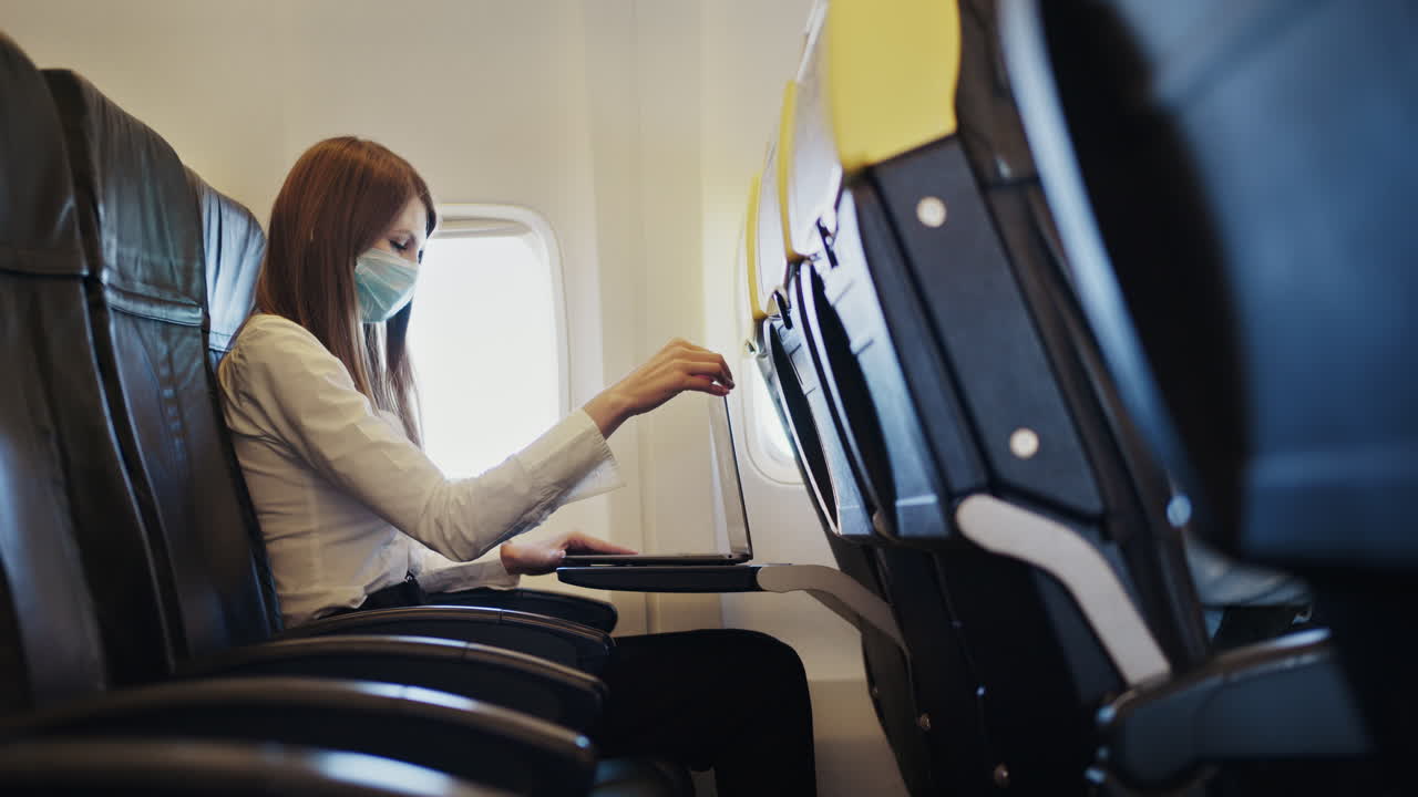 Woman working on a laptop in an airplane during a flight.