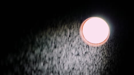 un haz direccional de luz y una fina lluvia frente a él en un video de cámara lenta de fondo negro