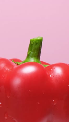 a vibrant red bell pepper beautifully highlighting its freshness against a soft, tranquil pink backdrop