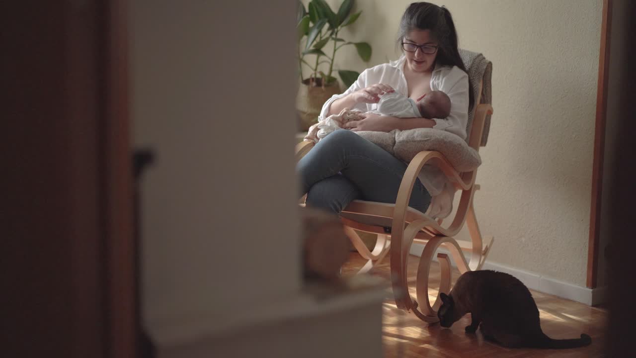 madre amamantando bebé recién nacido irreconocible en silla de mecerse