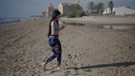 woman walking on beach with phone
