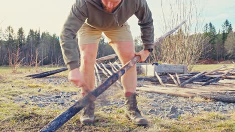 a man is charring the wooden poles to harden their surface and protect them from rot and insects - close up